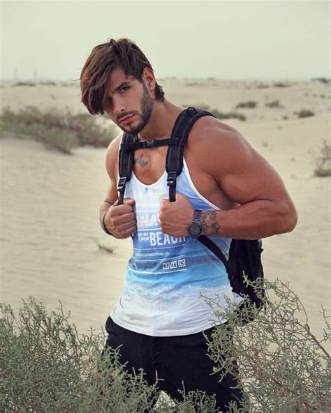 A Man Standing In The Sand With His Back To The Camera Giving Thumbs Up