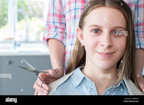 Portrait Of Mother Cutting Teenage Daughters Hair At Home During