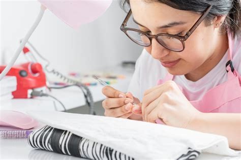 Hermosa joven latina limpiándose las uñas con un empujador de cutículas para una manicura Foto