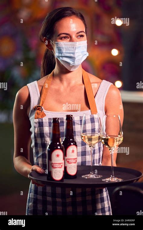 Portrait Of Female Server Wearing Face Mask Holding Tray Of Drinks In