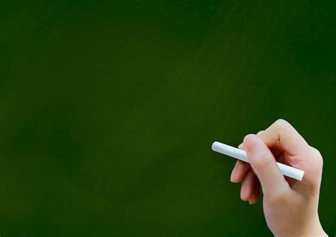 Premium Photo Close Up Of Hand Holding Chalk Over Green Background