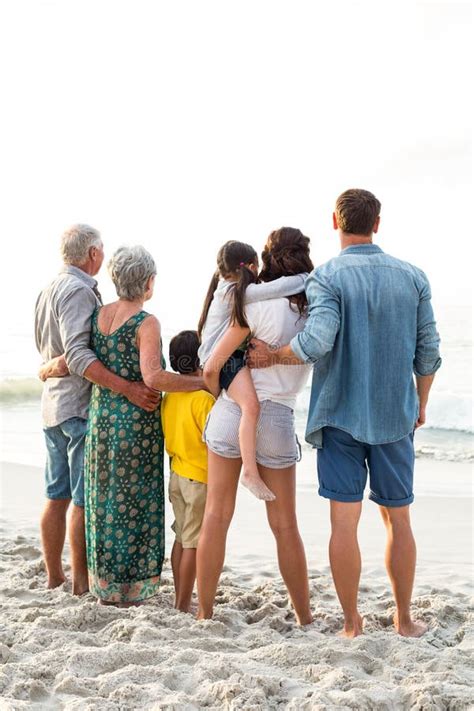 Vista Posterior De Una Familia Feliz Que Presenta En La Playa Imagen De