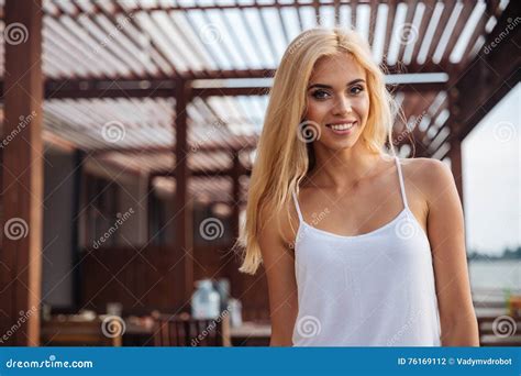 Smiling Woman With Long Blonde Hair Standing Outdoors Stock Photo