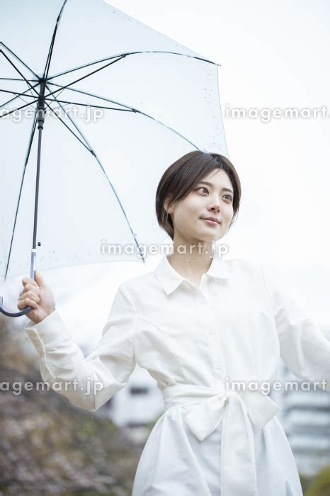 雨の中傘をさして歩く白いワンピースを着た若い女性の写真素材 164115747 イメージマート