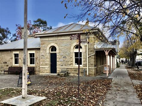 An Old Stone Building Sitting On The Side Of A Road Next To A Street Sign