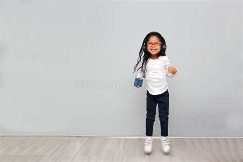 4 Year Old Brunette Latin Girl With Glasses Listens To Music In Her Headphones Connected To Her