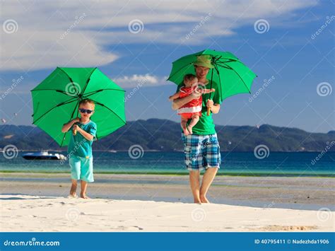 Familia Con Los Paraguas En Vacaciones Tropicales De La Playa Imagen De