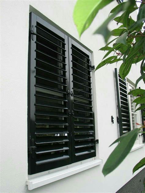 An Open Window With Black Shutters On The Side Of A White Building Next