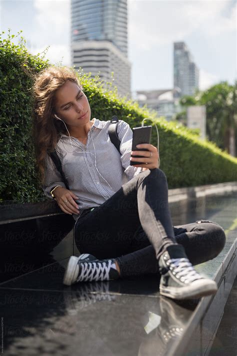 Young Female Sitting Outside With Her Phone Del Colaborador De Stocksy Jovo Jovanovic Stocksy