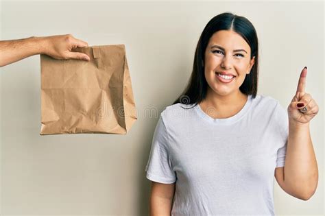 Beautiful Brunette Woman With Take Away Paper Bag Smiling With An Idea
