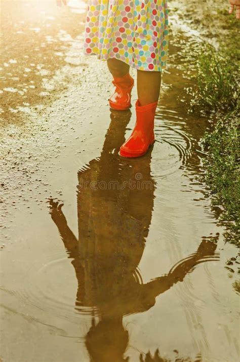 Child Wearing Orange Rain Boots Walking Into A Puddle Stock Image