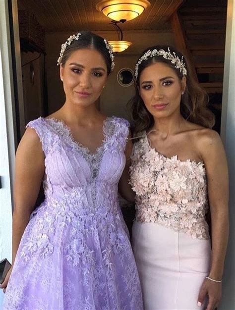 Two Women Standing Next To Each Other In Formal Wear And One Is Wearing