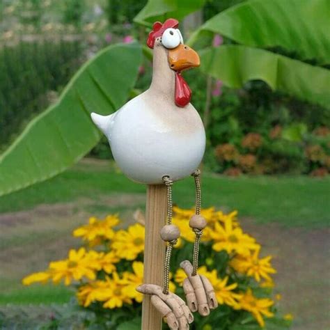 A White Chicken On Top Of A Wooden Pole With Yellow Flowers In The Back