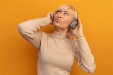 Heureux jolie blonde femme slave sur les écouteurs lève les yeux sur l