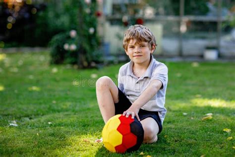 Happy Active Kid Boy Playing Soccer With Ball In German Flag Colors