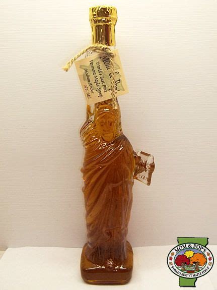 A Glass Bottle With A Statue Holding A Card In It S Hand And A Label On Top