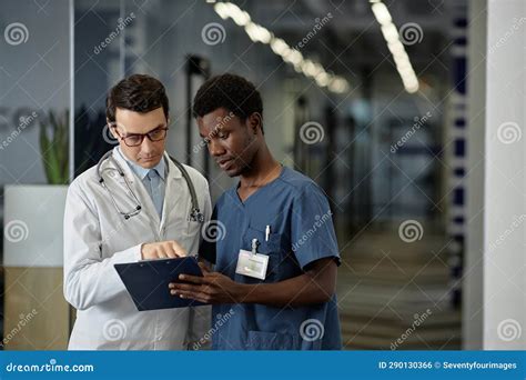 Confident Mature Physician In Lab Coat Pointing At Medical Document In