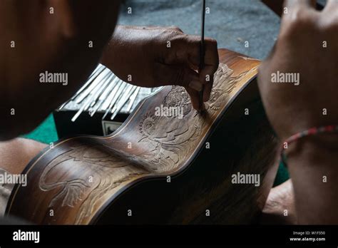 A Guitar Craftsman Are Carving A Classical Guitars Made From Wood With Balinese Pattern In A