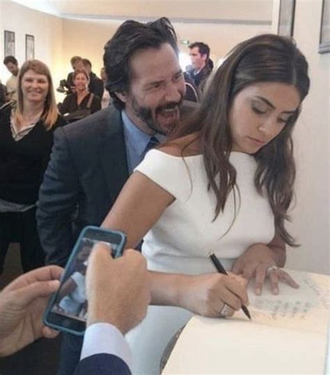 A Woman Signing Autographs For A Man In A Suit And Tie At An Event