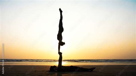 Silhouette of fit sporty couple practicing acrobatic yoga with partner ...