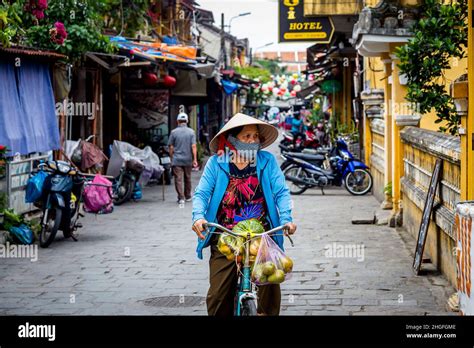 Vietnamese Lady Rides Her Bike Toward The Camera Carrying Bags Of Fruit