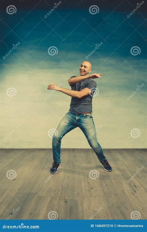 Cool Bald Man In A Gray T Shirt And Jeans Jumping And Fooling Around