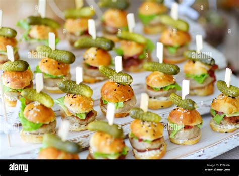 Delicious one bite mini burgers served on a party or wedding reception. Plates with assorted ...