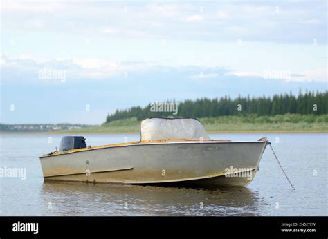 Old Metal Boat Is In Calm Water With Reflection Of Clouds Was Chained