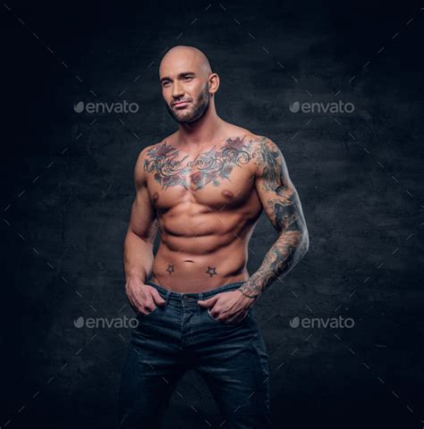 Shaved Head Muscular Male With Tattoos On His Torso Over Grey V Stock