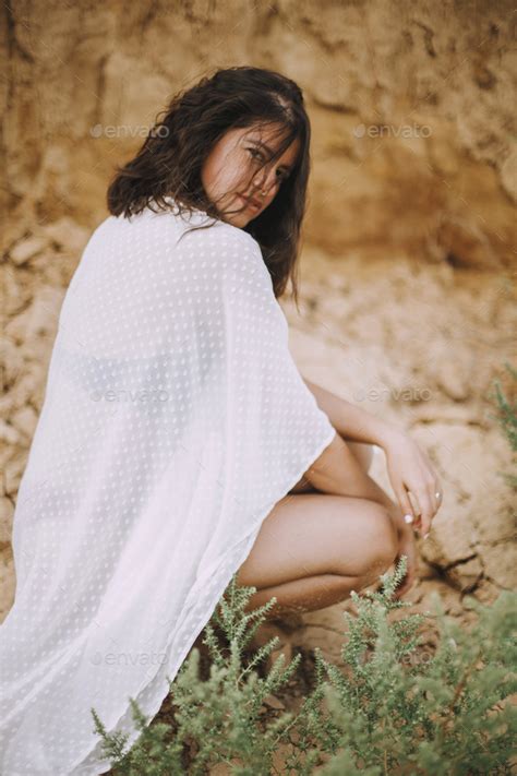 Boho Girl With Sensual Look In White Summer Dress Sitting On Beach