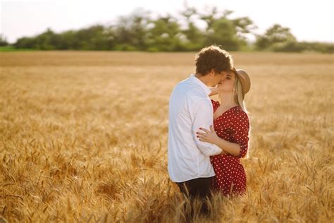 Joven pareja feliz abrazándose en un campo de trigo al atardecer