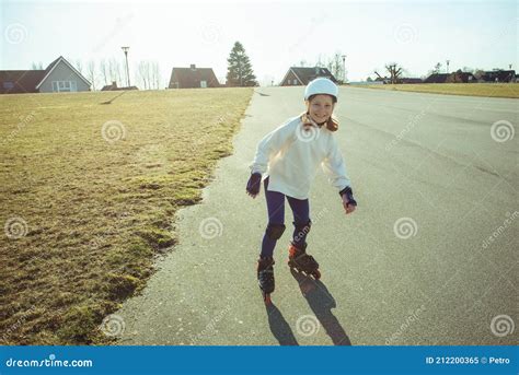 Happy Child Girl In White Helmet Inline Skates And Safety Equipment