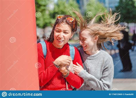 Las Mujeres Divertidas Se Esconden De Un Fuerte Viento Imagen De