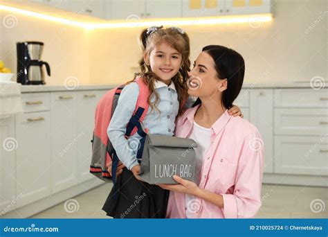 Young Mother Helping Her Little Child Get Ready For School In Kitchen