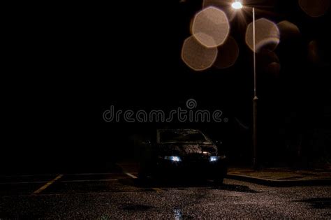 A Black Car with Headlights on, Under a Street Light on a Dark Wet Moody Night Stock Image ...