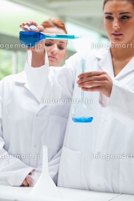 Portrait of scientists pouring liquid into a flask in a laboratoryの写真素材