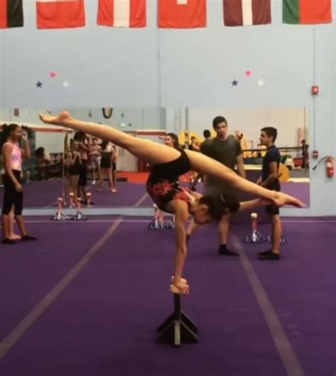 A Woman Doing A Handstand On Top Of A Pole In An Indoor Gym