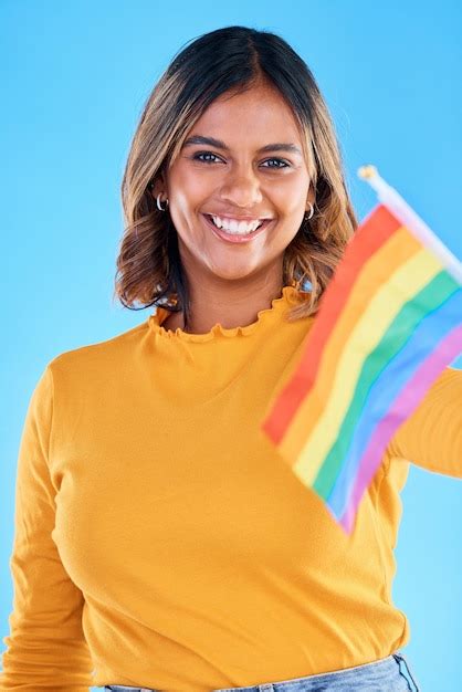 Bandera de retrato y gay con una mujer de fondo azul en el estudio sintiéndose orgullosa de su