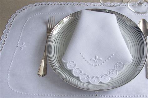 A White Place Setting With Silverware And Napkins On A Linen