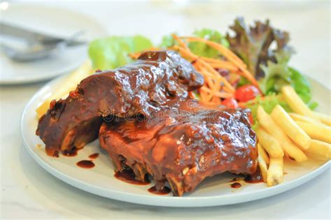 Costilla De Cerdo De La Barbacoa Con Las Patatas Fritas Imagen De