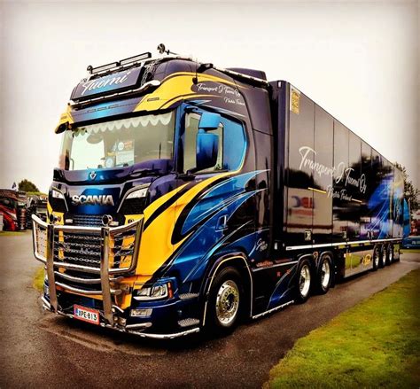 A Blue And Yellow Semi Truck Driving Down The Road