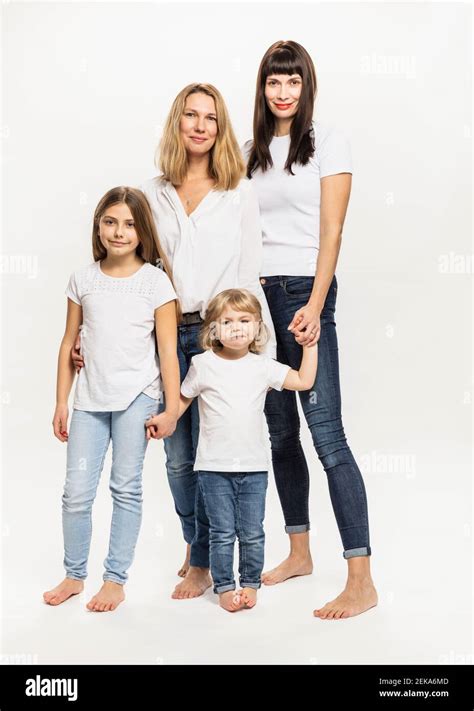 Smiling Women Standing With Daughters Against White Background In