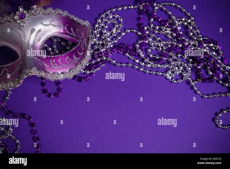 A purple mardi gras mask on a purple background with beads. Carnival ...