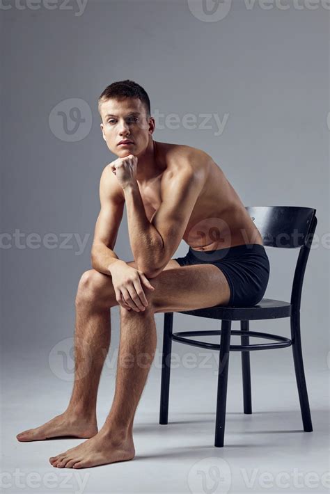 Sporty Man With A Pumped Up Body In Black Shorts Sits On A Chair