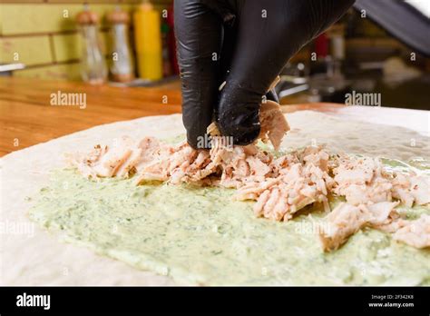 Proceso de cocción de burritos El cocinero añade carne a la pita con