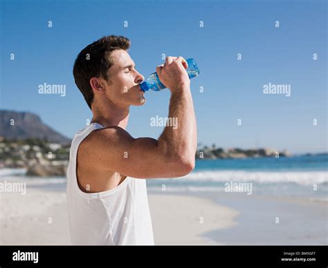 Young Man Drinking Water On Beach Stock Photo Alamy