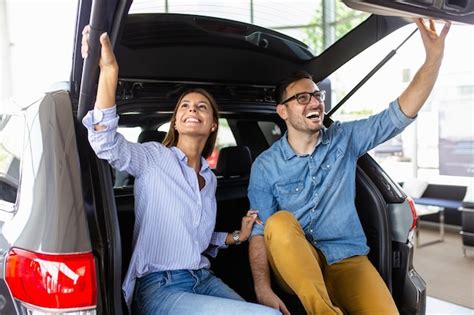 Hermosa pareja joven en la sala de exposición de autos eligiendo un