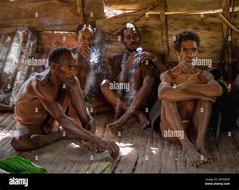 Los hombres de la tribu Korowai están sentados en una casa tradicional