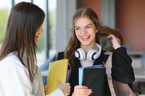 Duas mulheres jovens um livro conversando em pé no corredor da