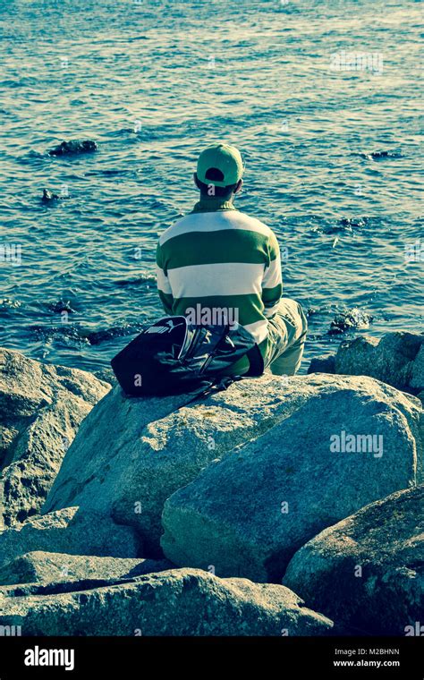 Man Sitting On Rocks Looking Out To Sea Stock Photo Alamy